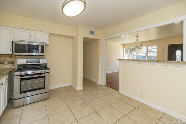 kitchen featuring light tile patterned floors, stainless steel appliances, backsplash, and white cabinets