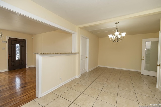 entryway featuring beam ceiling, a notable chandelier, baseboards, and light tile patterned floors