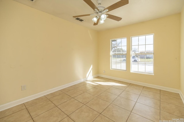 empty room featuring light tile patterned floors, baseboards, visible vents, and a ceiling fan