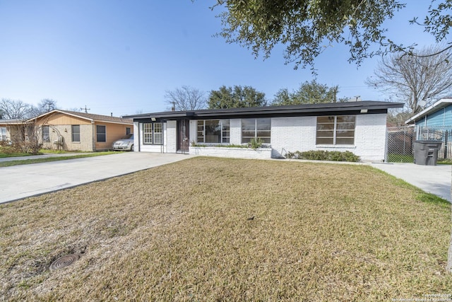 view of front of home with brick siding, driveway, a front lawn, and fence