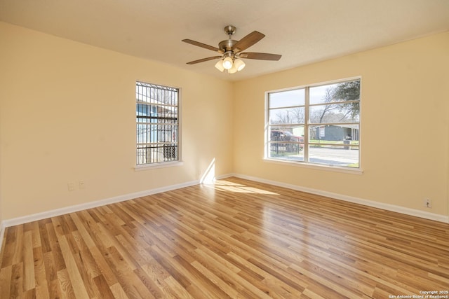 spare room featuring ceiling fan, light wood finished floors, and baseboards