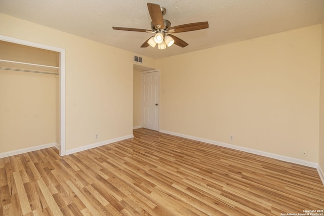 unfurnished bedroom featuring light wood finished floors, baseboards, visible vents, and a textured ceiling