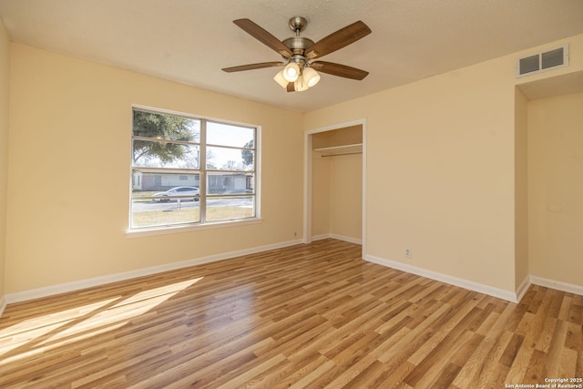 unfurnished bedroom with light wood-style flooring, a ceiling fan, visible vents, baseboards, and a closet