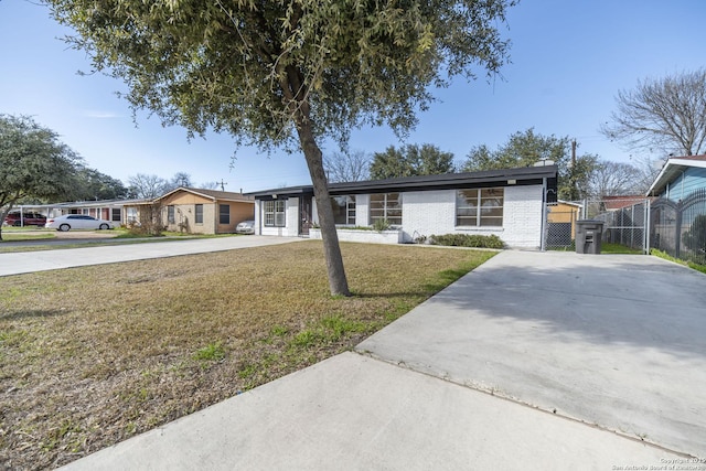 view of front of property featuring concrete driveway, a gate, fence, a front yard, and brick siding