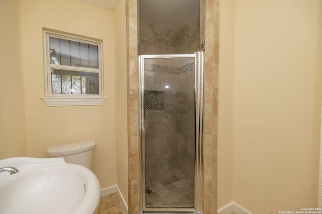 bathroom featuring a stall shower, toilet, a sink, and baseboards