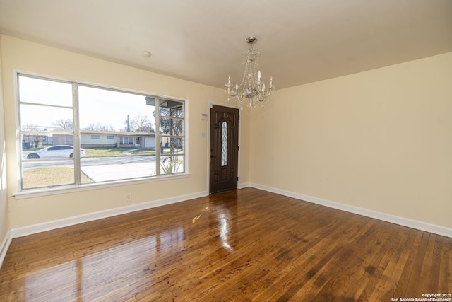 unfurnished dining area featuring baseboards, a notable chandelier, and hardwood / wood-style floors