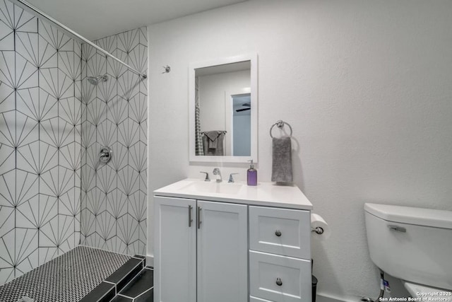 bathroom featuring a tile shower, vanity, and toilet