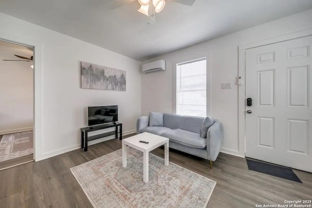 living area featuring dark wood-style flooring, a wall unit AC, ceiling fan, and baseboards