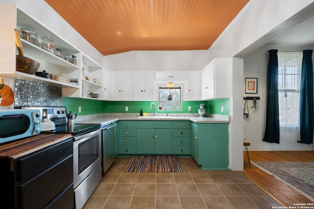 kitchen with a sink, tile patterned flooring, stainless steel appliances, green cabinets, and backsplash