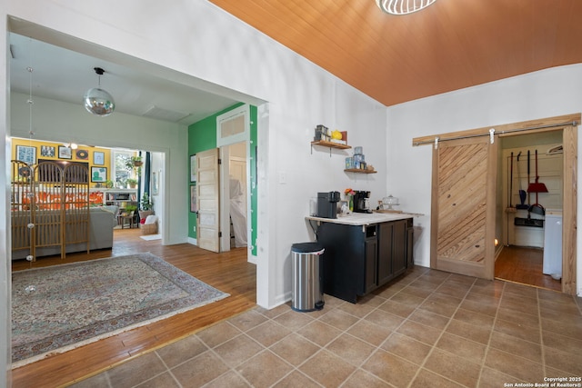 kitchen with a barn door, baseboards, light wood-style flooring, and light countertops