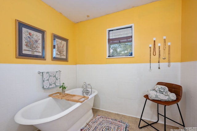 full bath featuring a soaking tub, wainscoting, tile walls, and tile patterned floors