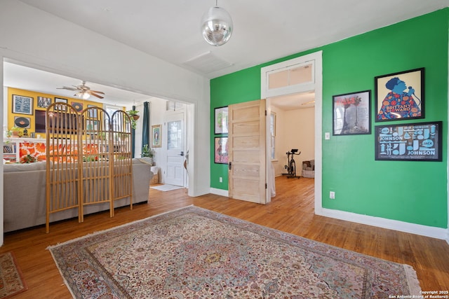 interior space with ceiling fan, baseboards, and wood finished floors