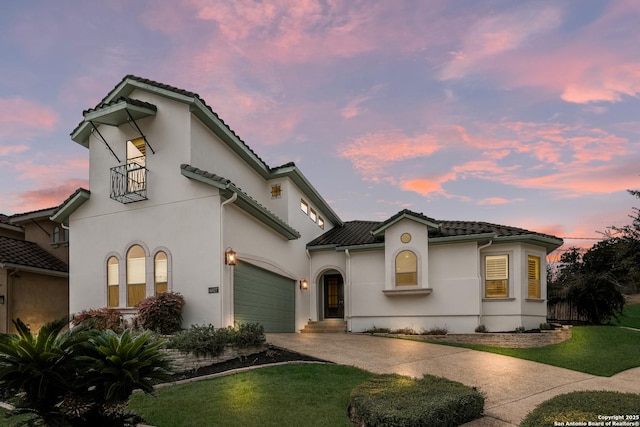 mediterranean / spanish home featuring a yard, driveway, a tiled roof, and stucco siding