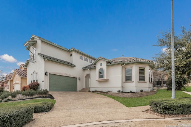 mediterranean / spanish house featuring a garage, concrete driveway, a tiled roof, fence, and stucco siding