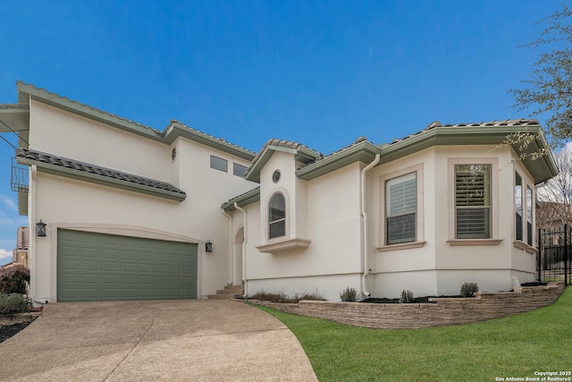 mediterranean / spanish-style house with an attached garage, fence, driveway, a tiled roof, and stucco siding