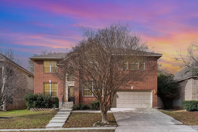 traditional-style house featuring a garage, concrete driveway, brick siding, and a yard