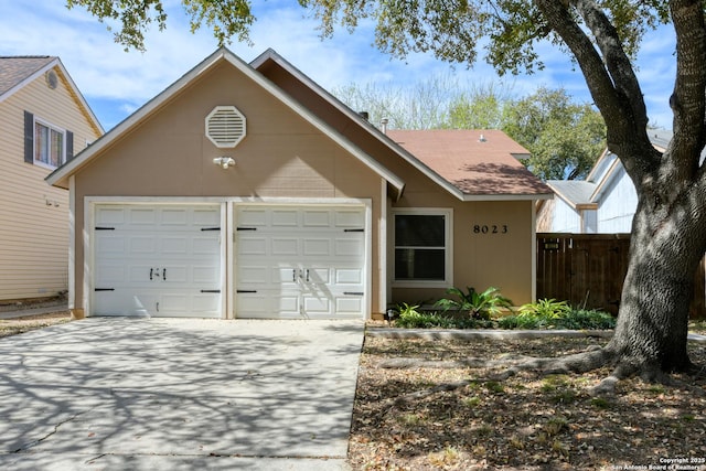 view of front facade with driveway, an attached garage, and fence