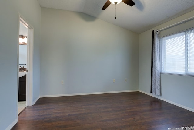 empty room with baseboards, lofted ceiling, wood finished floors, and a ceiling fan