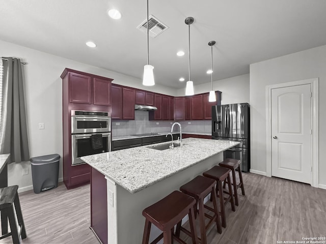 kitchen featuring visible vents, stainless steel double oven, dark brown cabinets, refrigerator with ice dispenser, and a sink