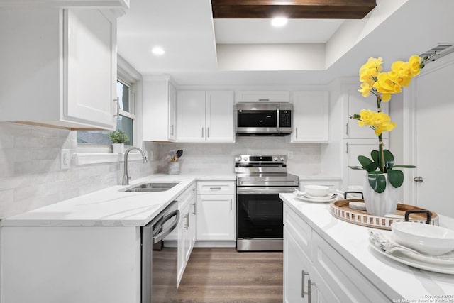 kitchen with stainless steel appliances, white cabinets, a sink, and wood finished floors