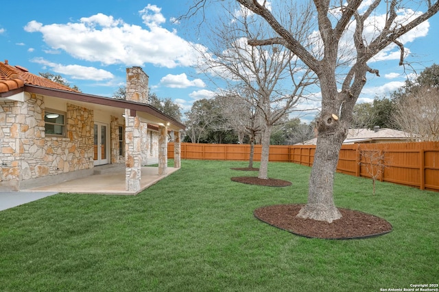 view of yard with french doors, a fenced backyard, and a patio