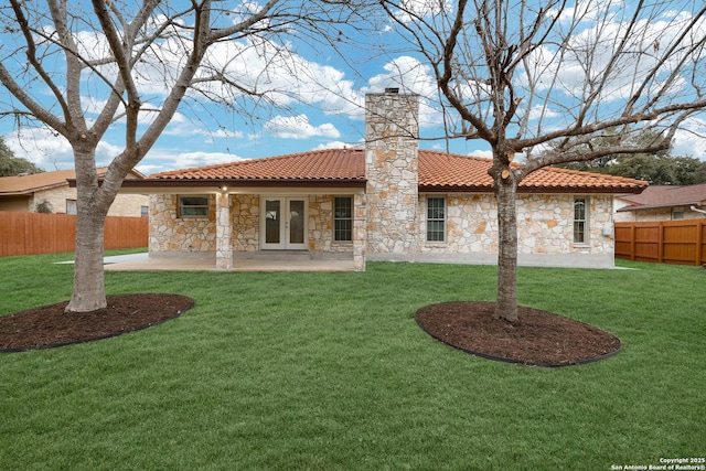 rear view of property featuring a lawn, a patio, a chimney, fence, and french doors