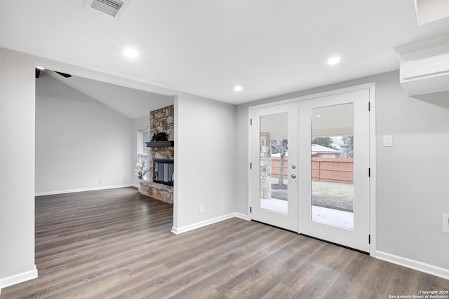 unfurnished living room featuring french doors, visible vents, a stone fireplace, and wood finished floors