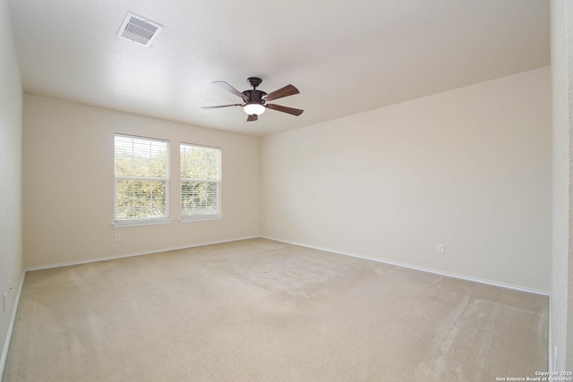 empty room featuring baseboards, visible vents, a ceiling fan, and light colored carpet