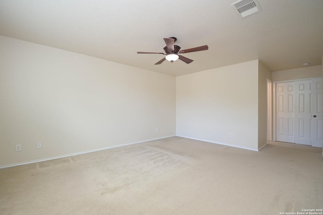 spare room featuring light carpet, a ceiling fan, visible vents, and baseboards