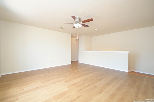 empty room with ceiling fan, light wood-style flooring, visible vents, and baseboards