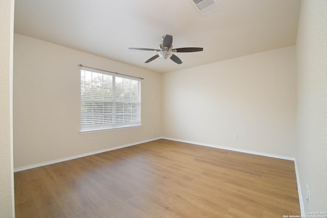 empty room with ceiling fan, wood finished floors, visible vents, and baseboards