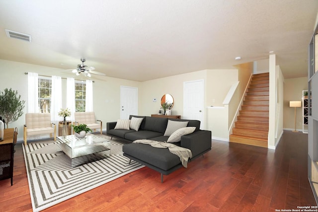 living area with wood finished floors, a ceiling fan, visible vents, stairs, and baseboards