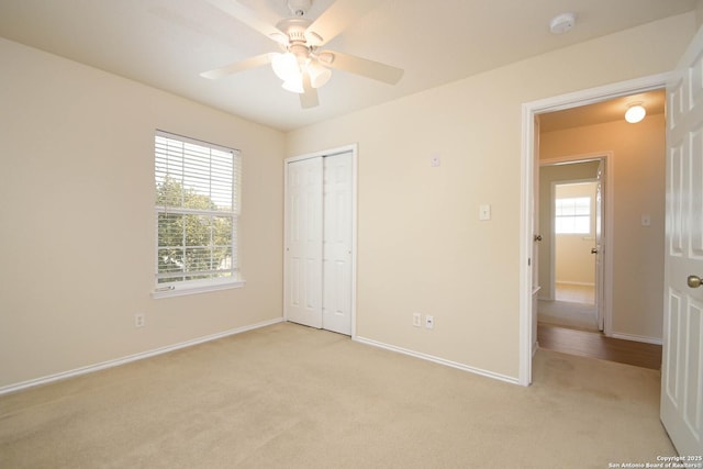 unfurnished bedroom featuring a closet, light colored carpet, baseboards, and multiple windows