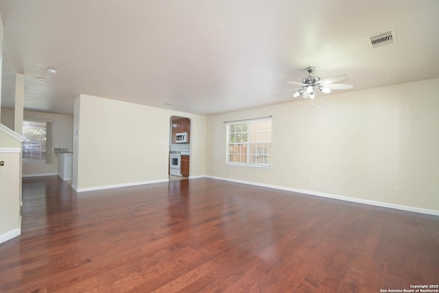 unfurnished living room with a wealth of natural light, baseboards, and wood finished floors