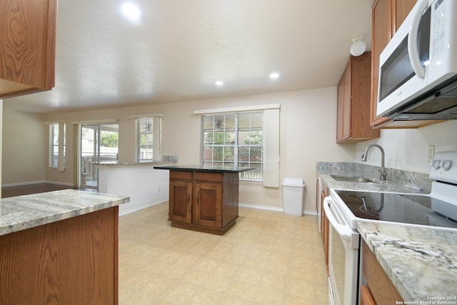 kitchen with light stone counters, brown cabinets, light floors, a sink, and white appliances