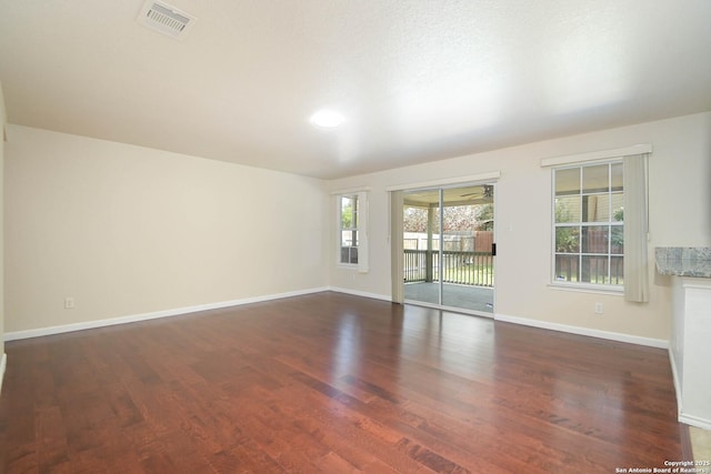 unfurnished room with baseboards, visible vents, and wood finished floors