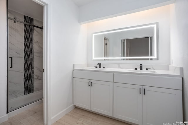 full bathroom with double vanity, a sink, and a marble finish shower