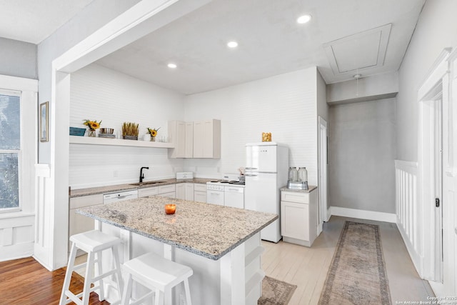 kitchen featuring a breakfast bar area, a kitchen island, a sink, light wood-style floors, and freestanding refrigerator