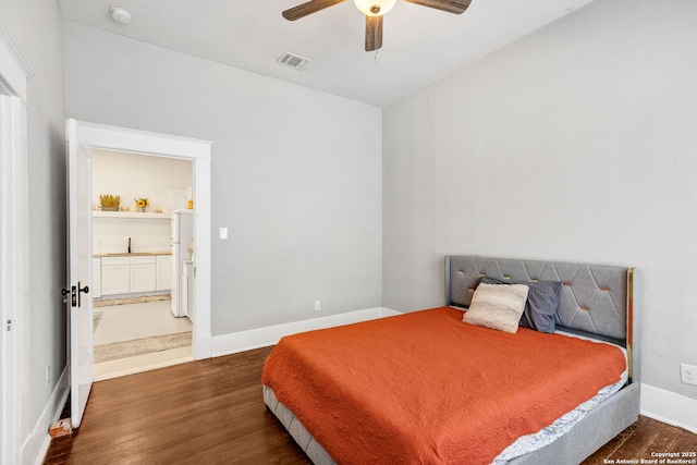 bedroom featuring freestanding refrigerator, dark wood-style flooring, ceiling fan, and baseboards