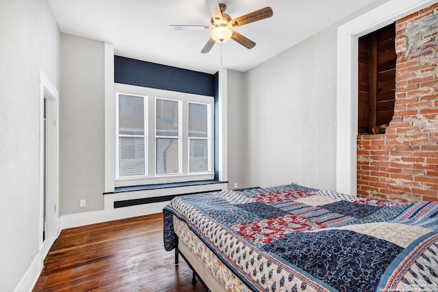 bedroom featuring brick wall, baseboards, ceiling fan, and wood finished floors