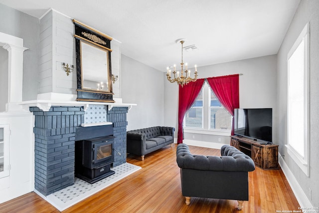 living room featuring a wood stove, baseboards, visible vents, and wood finished floors