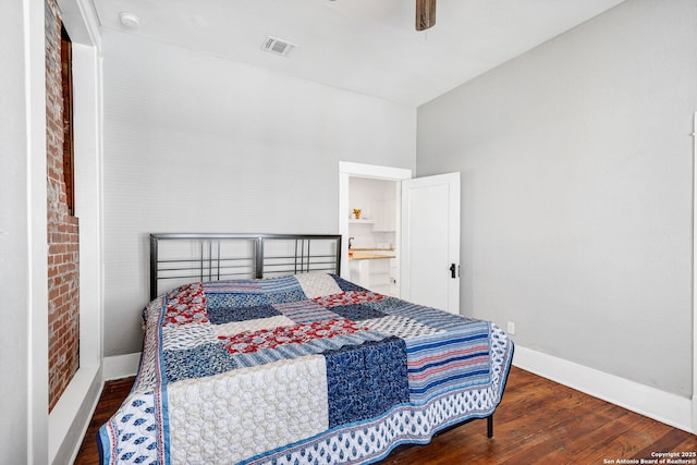 bedroom with visible vents, ceiling fan, brick wall, wood finished floors, and baseboards