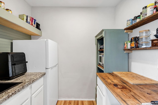 kitchen featuring wood counters, white cabinetry, open shelves, and freestanding refrigerator