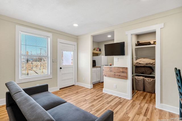 living area featuring light wood-style floors, baseboards, and recessed lighting