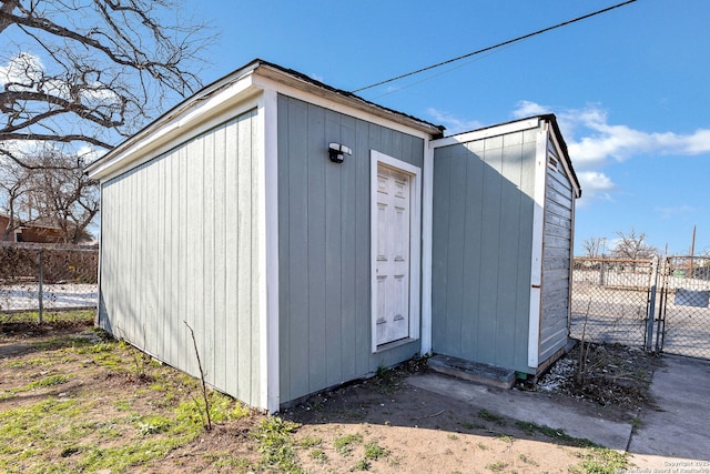 view of shed featuring fence and a gate