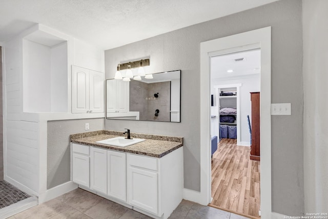 bathroom featuring visible vents, a textured wall, vanity, a textured ceiling, and tiled shower