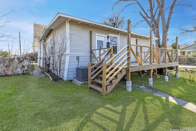 rear view of property featuring a gate, fence, a deck, a yard, and central AC