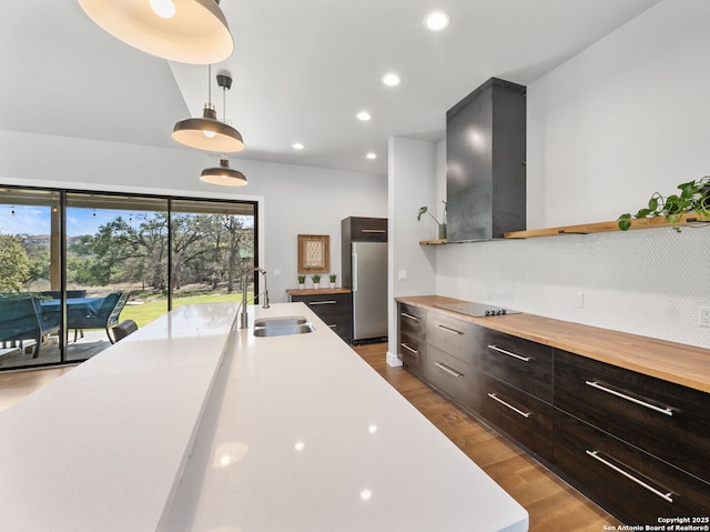 kitchen with modern cabinets, dark wood-style flooring, fridge, a sink, and exhaust hood