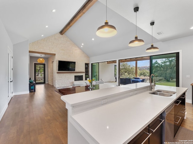 kitchen with open floor plan, light countertops, lofted ceiling with beams, and a sink