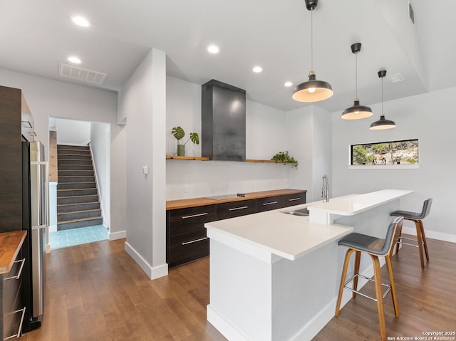 kitchen with open shelves, butcher block counters, visible vents, a sink, and a kitchen breakfast bar